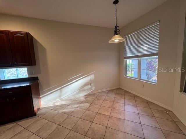 A kitchen dining area features dark wood cabinets, tile flooring, and a hanging pendant light — 6517 TAILFEATHER WAY, BRADENTON, FL