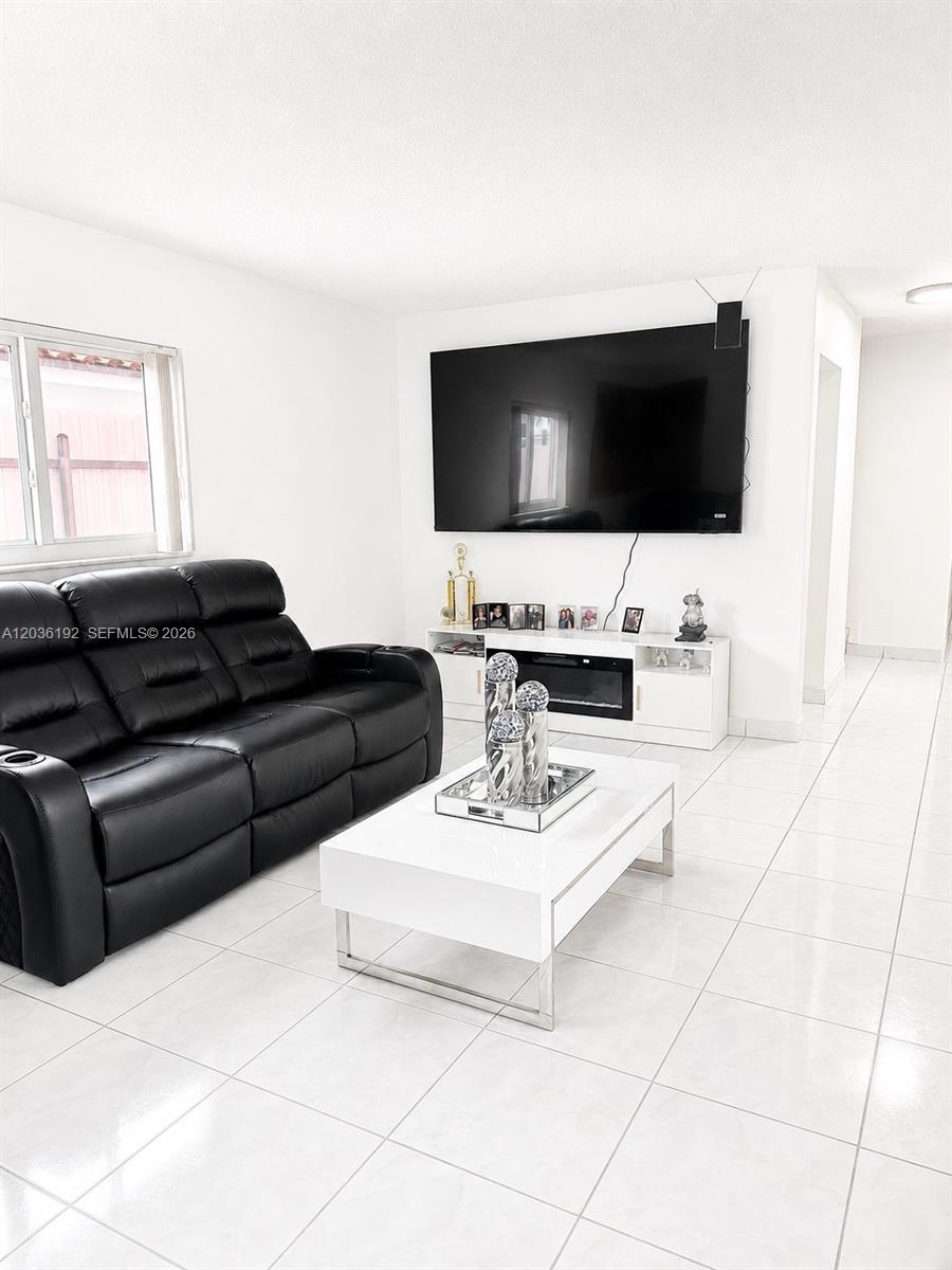 A living room features a black leather sofa, a white coffee table, and a wall-mounted television — 380 W 45th St, Hialeah FL 33012, HIALEAH, FL