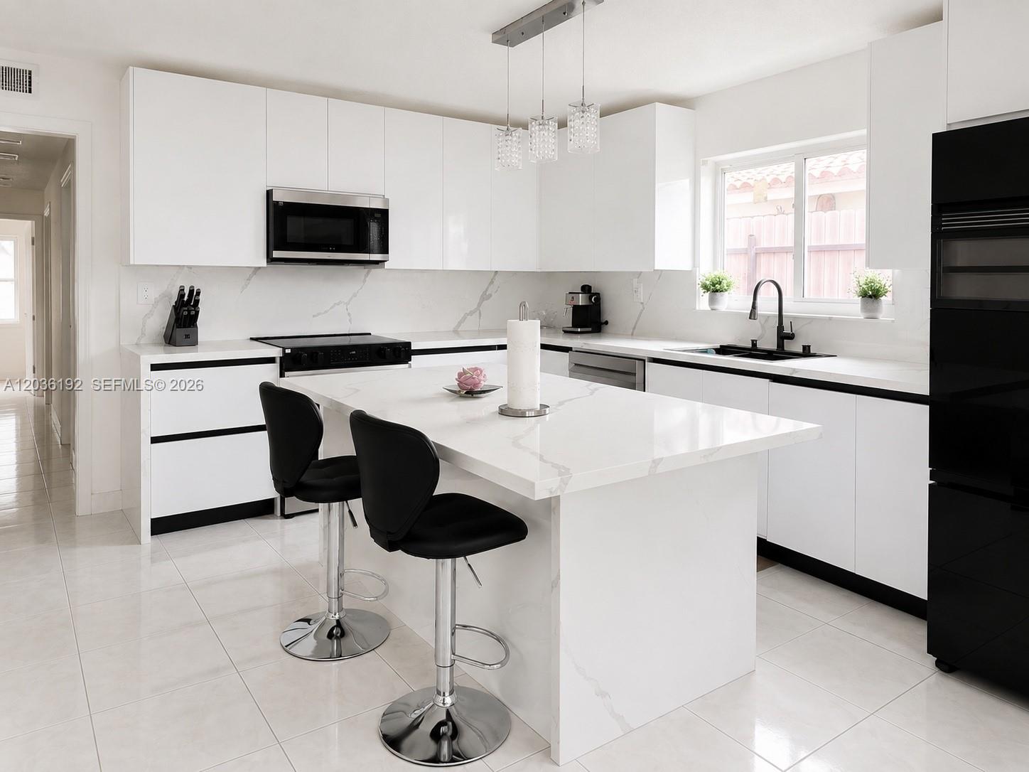 A modern kitchen features white cabinets, marble-patterned countertops, a central island, and black appliances — 380 W 45th St, Hialeah FL 33012, HIALEAH, FL