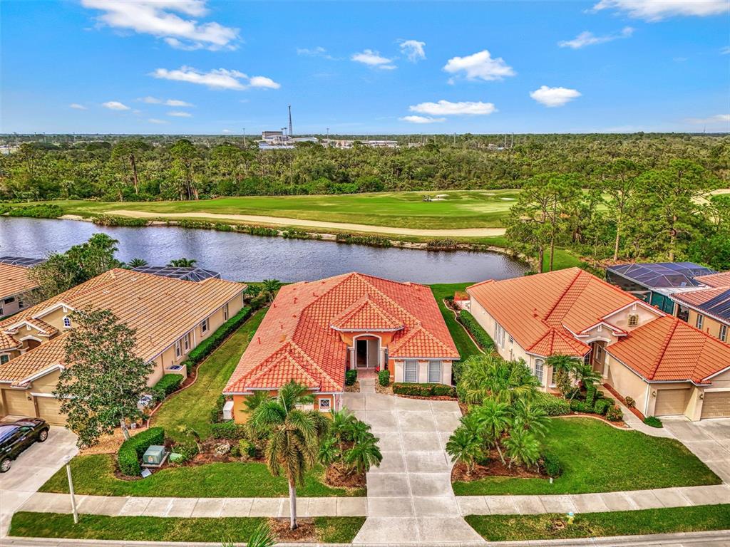 An aerial view shows three houses with orange tile roofs near a lake and golf course — 1151 CREEK NINE DRIVE, NORTH PORT, FL