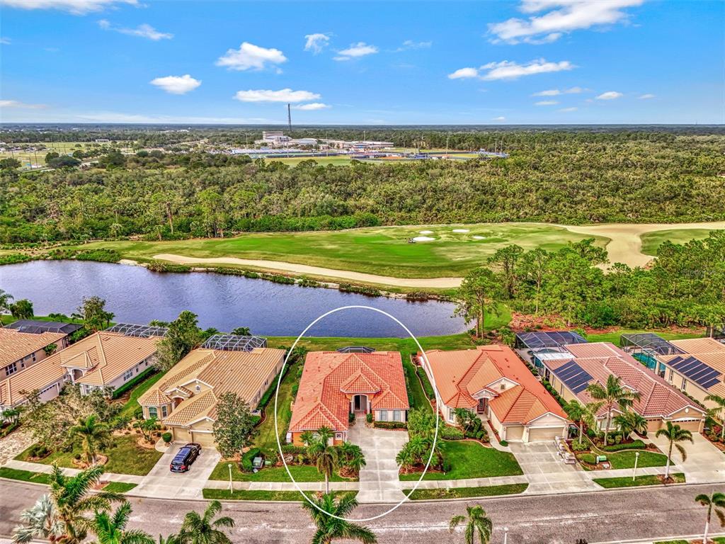 An aerial view shows a residential house with a red tile roof near a lake — 1151 CREEK NINE DRIVE, NORTH PORT, FL