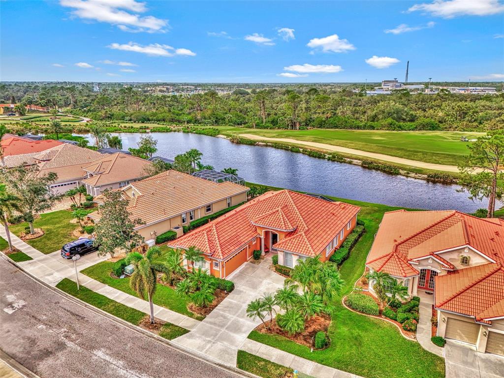 An aerial view shows suburban houses with orange tile roofs near a pond and golf course — 1151 CREEK NINE DRIVE, NORTH PORT, FL