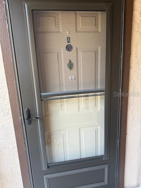 A dark-framed storm door with a screen panel is mounted over a white entry door — 4022 BEAVER LANE UNIT 1000A, PORT CHARLOTTE, FL