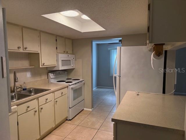 A kitchen with light-colored cabinets, white appliances, tile flooring, and a skylight — 4022 BEAVER LANE UNIT 1000A, PORT CHARLOTTE, FL