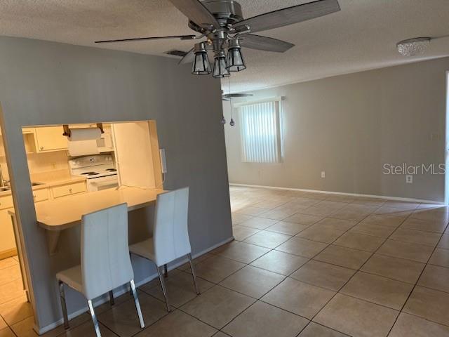 A kitchen with a breakfast bar and two chairs opens into a tiled living area — 4022 BEAVER LANE UNIT 1000A, PORT CHARLOTTE, FL
