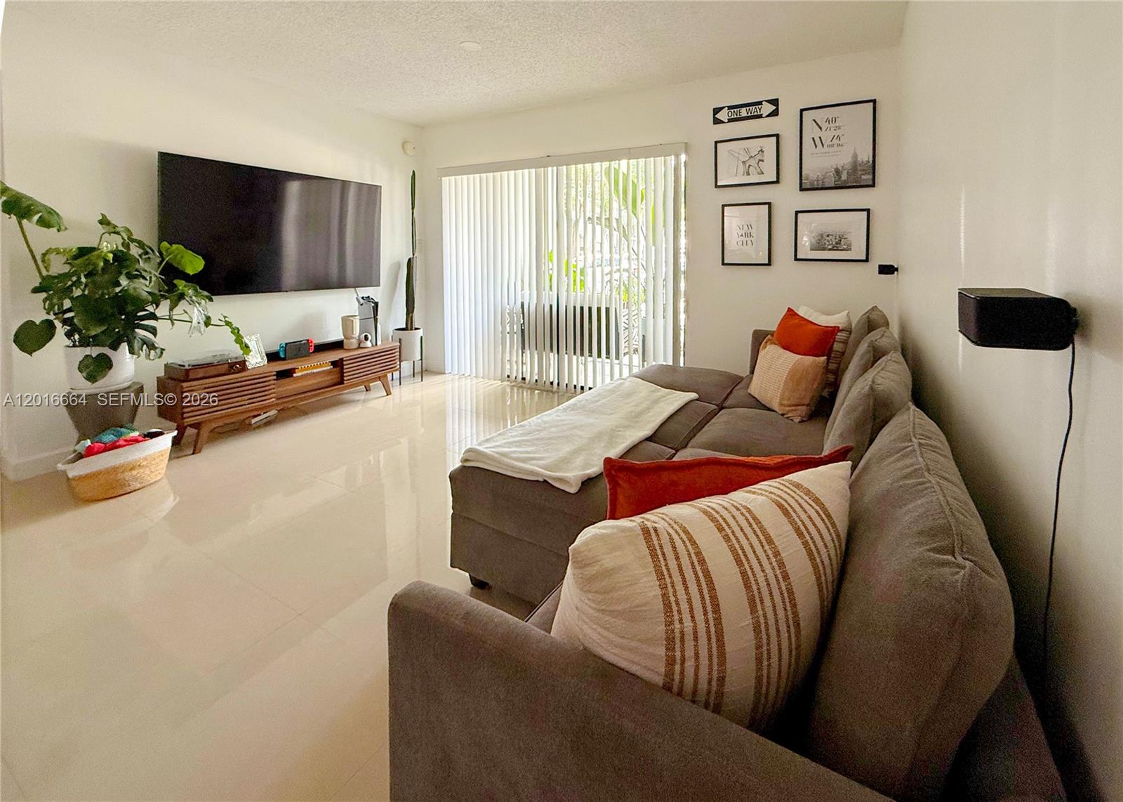 A living room features a large television, a sectional sofa, and light-colored tile flooring — 530 S Park Rd # 11, Hollywood FL 33021, HOLLYWOOD, FL
