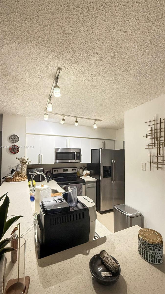 A kitchen features white cabinets, stainless steel appliances, and a track lighting system — 530 S Park Rd # 11, Hollywood FL 33021, HOLLYWOOD, FL