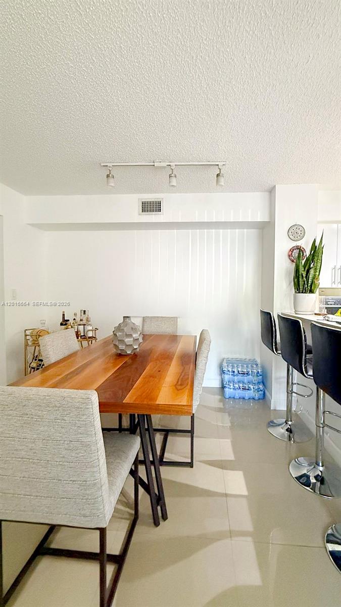 A dining area features a wooden table, upholstered chairs, and a bar counter with stools — 530 S Park Rd # 11, Hollywood FL 33021, HOLLYWOOD, FL