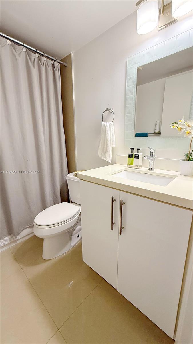 A bathroom features a white vanity, a toilet, and a shower with a gray curtain — 530 S Park Rd # 11, Hollywood FL 33021, HOLLYWOOD, FL