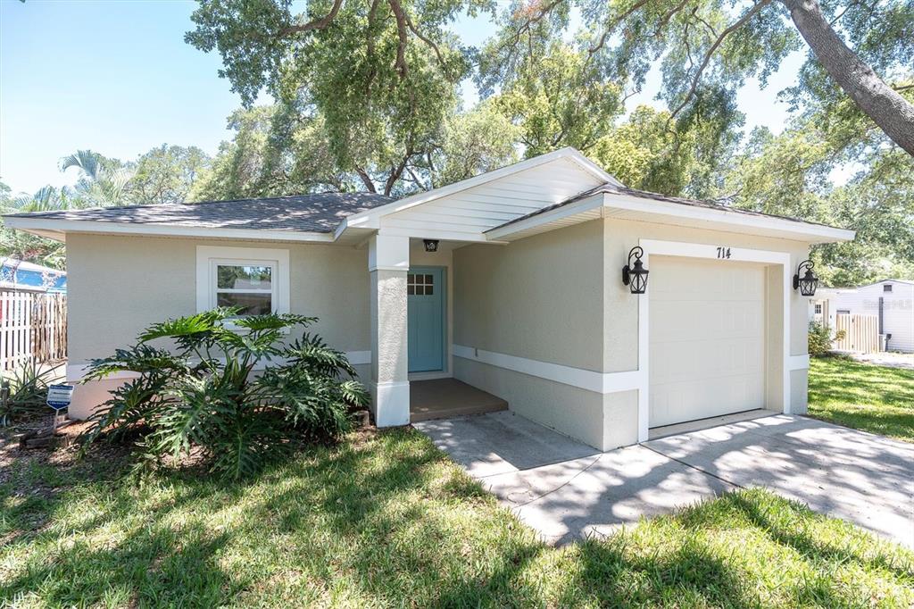 A single-story house with a light-colored exterior, a blue front door, and an attached garage — 714 3RD AVENUE NE, LARGO, FL