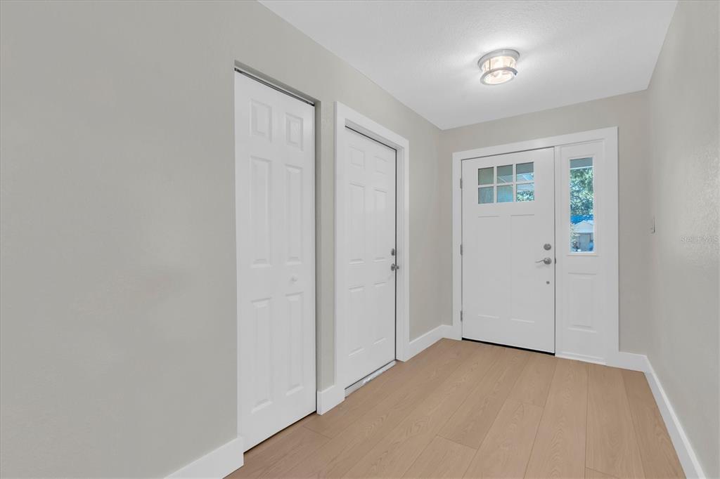 An entryway features light wood-look flooring, gray walls, a white front door, and two closets — 714 3RD AVENUE NE, LARGO, FL