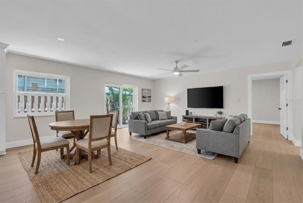 A living and dining area with light wood floors, gray sofas, and a round table — 714 3RD AVENUE NE, LARGO, FL