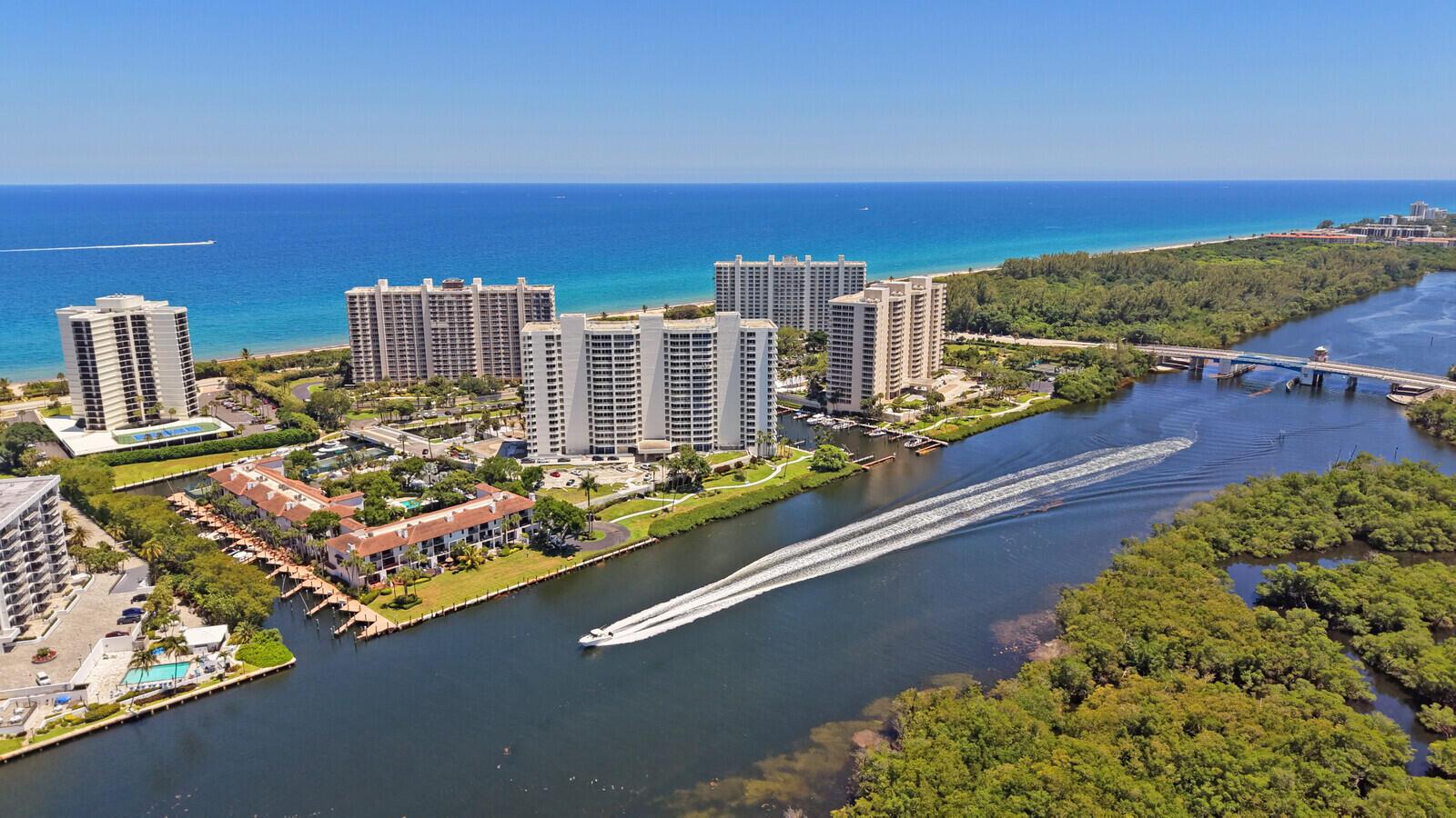 An aerial view shows high-rise condominiums, a canal with a boat, and a nearby bridge — 4501 N Ocean Boulevard # 04, Boca Raton FL 33431, BOCA RATON, FL