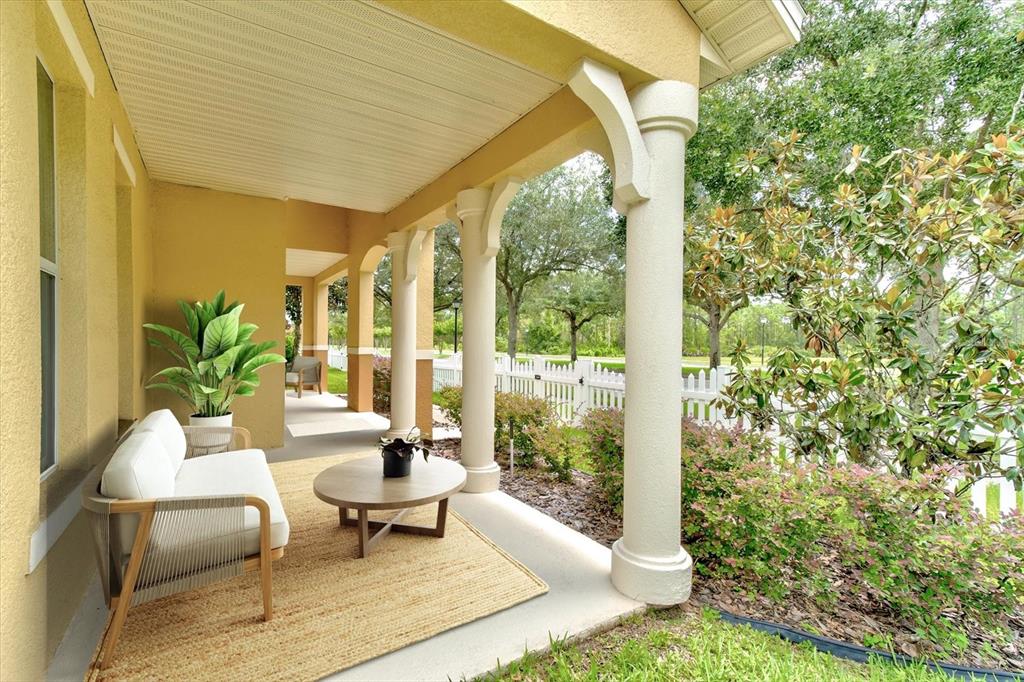 A covered porch features a white sofa, a round coffee table, and decorative columns — 2463 LACERTA DRIVE, ORLANDO, FL