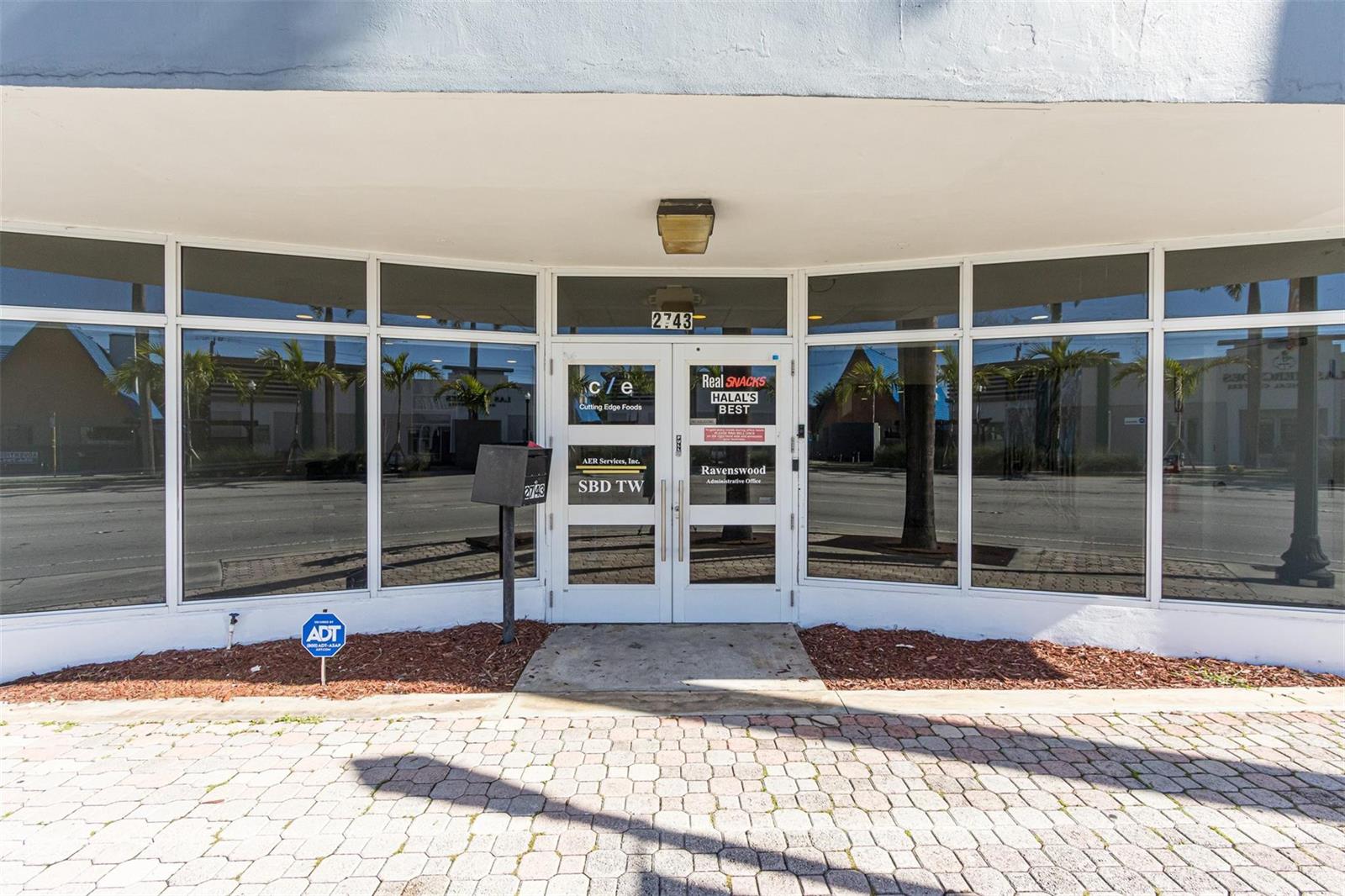 The exterior of a commercial building features glass storefront windows and double glass entry doors — 2743 Hollywood Boulevard, Hollywood FL 33020, HOLLYWOOD, FL