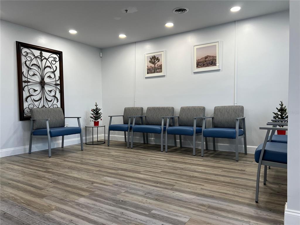 A waiting room features gray and blue chairs, wood-look flooring, and wall art — 105 BELLAGIO CIRCLE, SANFORD, FL
