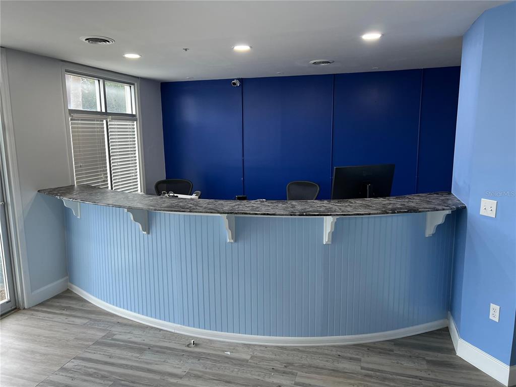 A curved reception desk with a marble-look countertop sits against a blue wall — 105 BELLAGIO CIRCLE, SANFORD, FL