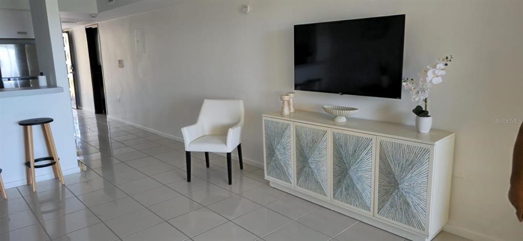 A white living room features a wall-mounted television above a decorative four-door sideboard cabinet — Palmas del Mar PALMANOVA UNIT 321, HUMACAO, PR