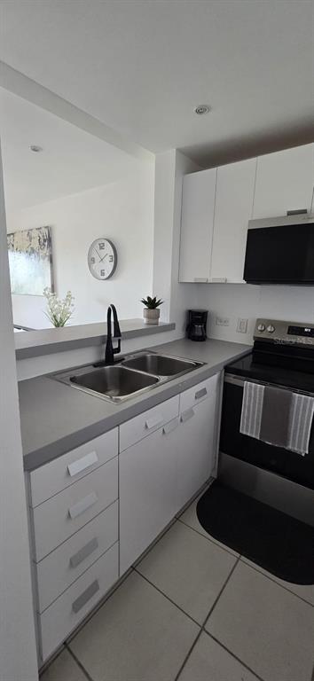 A kitchen features white cabinets, stainless steel appliances, a double sink, and tiled flooring — Palmas del Mar PALMANOVA UNIT 321, HUMACAO, PR