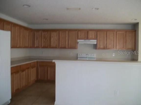 A kitchen features light wood cabinets, white appliances, and a peninsula counter overlooking the room — 72 ROLLINS LANE, PALM COAST, FL