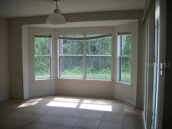 A dining area with tile flooring, a bay window, and a hanging light fixture — 72 ROLLINS LANE, PALM COAST, FL