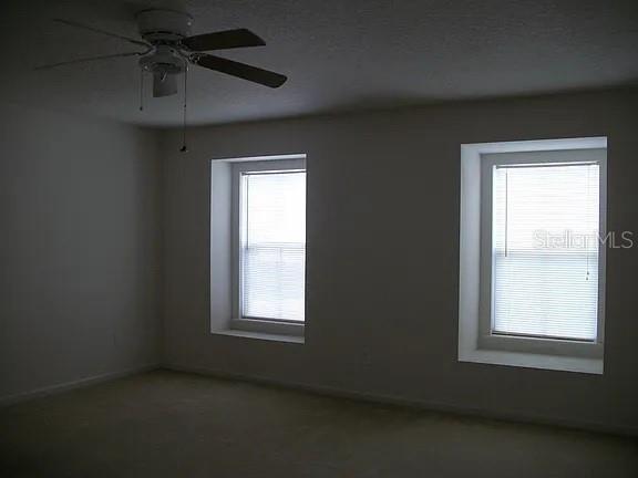 An empty bedroom with beige carpet, white walls, a ceiling fan, and two recessed windows — 72 ROLLINS LANE, PALM COAST, FL
