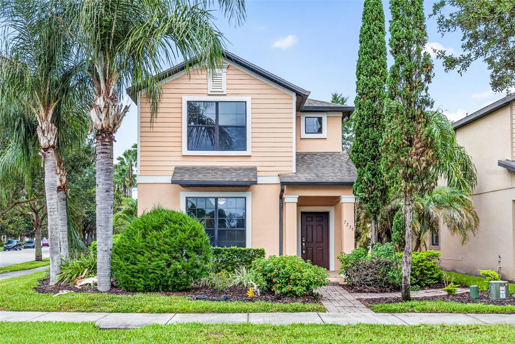 A two-story peach-colored house with a dark brown front door and a landscaped front yard — 7236 PENKRIDGE LANE, WINDERMERE, FL