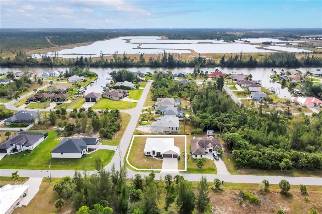An aerial view shows a single-story house with a white roof in a residential neighborhood — 15117 LYNEBURG AVENUE, PORT CHARLOTTE, FL