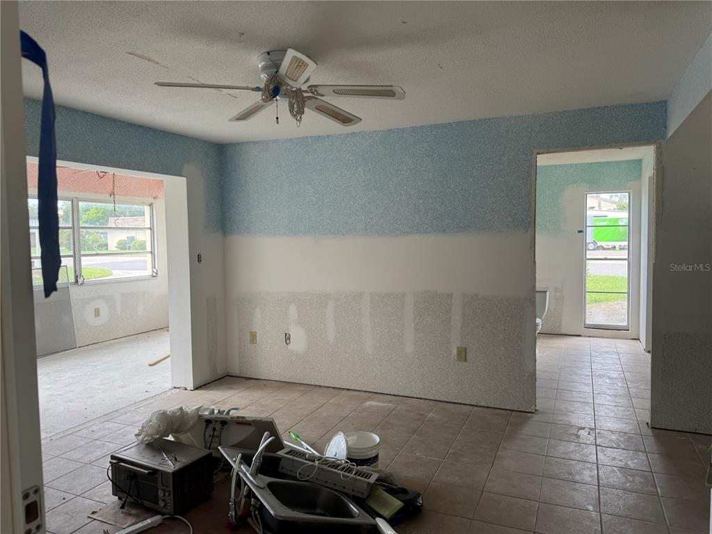 An interior view shows a room under renovation with partially painted walls and tiled floors — 5132 AMULET DRIVE UNIT 101, NEW PORT RICHEY, FL