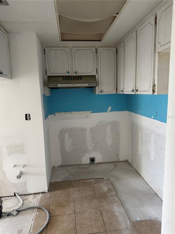 A kitchen under renovation with white cabinets, a blue tiled backsplash, and unfinished walls — 5132 AMULET DRIVE UNIT 101, NEW PORT RICHEY, FL