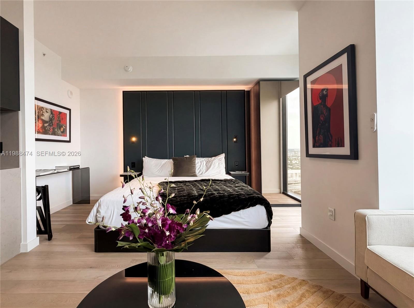A modern bedroom features a dark paneled headboard, a bed with a dark throw, and artwork — 20 NE 11th St # 4111, Miami FL 33132, MIAMI, FL