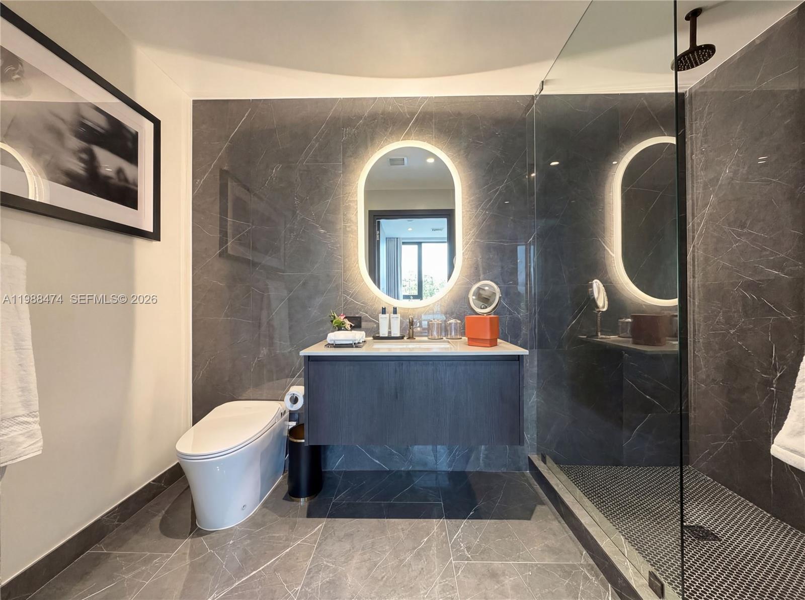 A modern bathroom features dark marble walls, a floating vanity, and a glass-enclosed shower — 20 NE 11th St # 4111, Miami FL 33132, MIAMI, FL