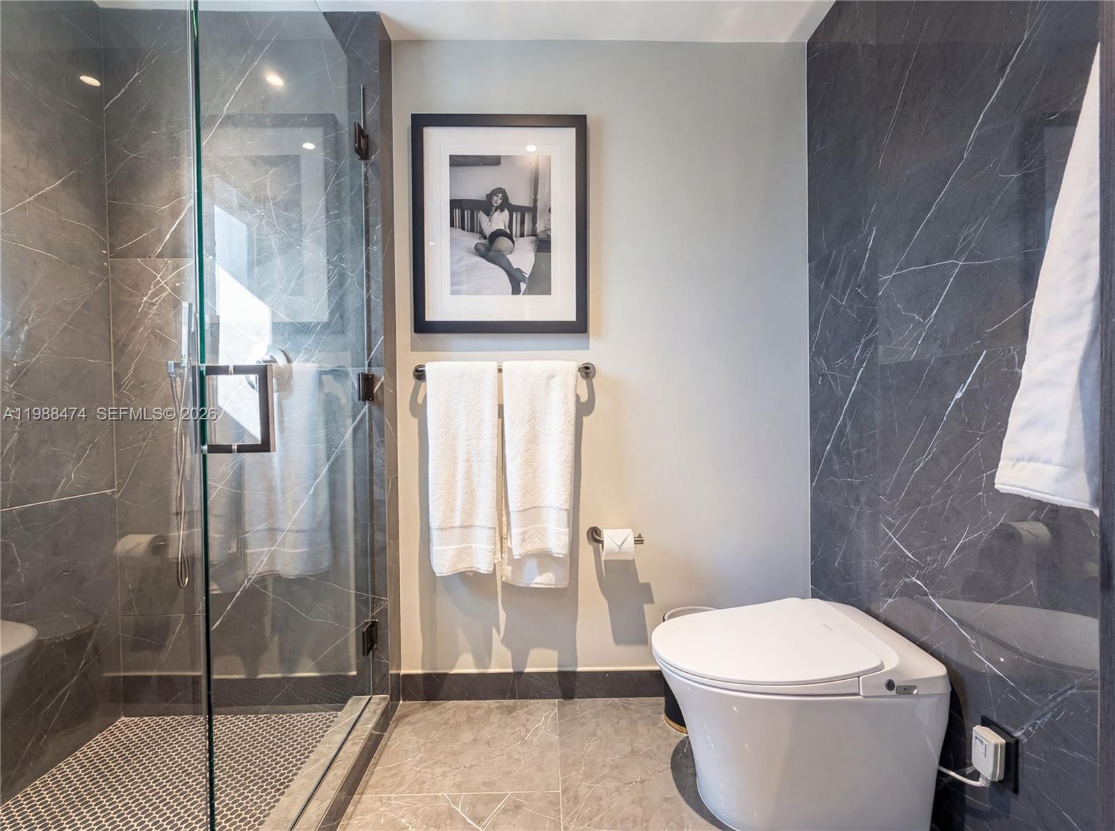 A modern bathroom features a glass-enclosed shower, a toilet, and dark marble-patterned wall tiles — 20 NE 11th St # 4111, Miami FL 33132, MIAMI, FL