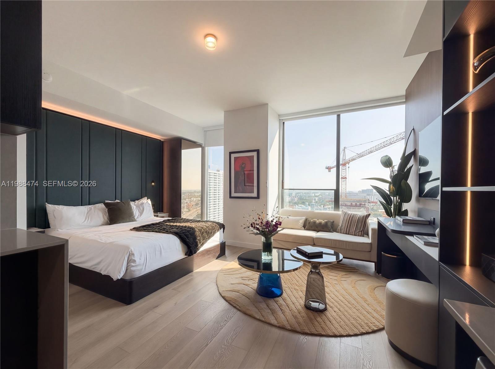 A modern bedroom features a dark paneled headboard, a seating area, and floor-to-ceiling windows — 20 NE 11th St # 4111, Miami FL 33132, MIAMI, FL