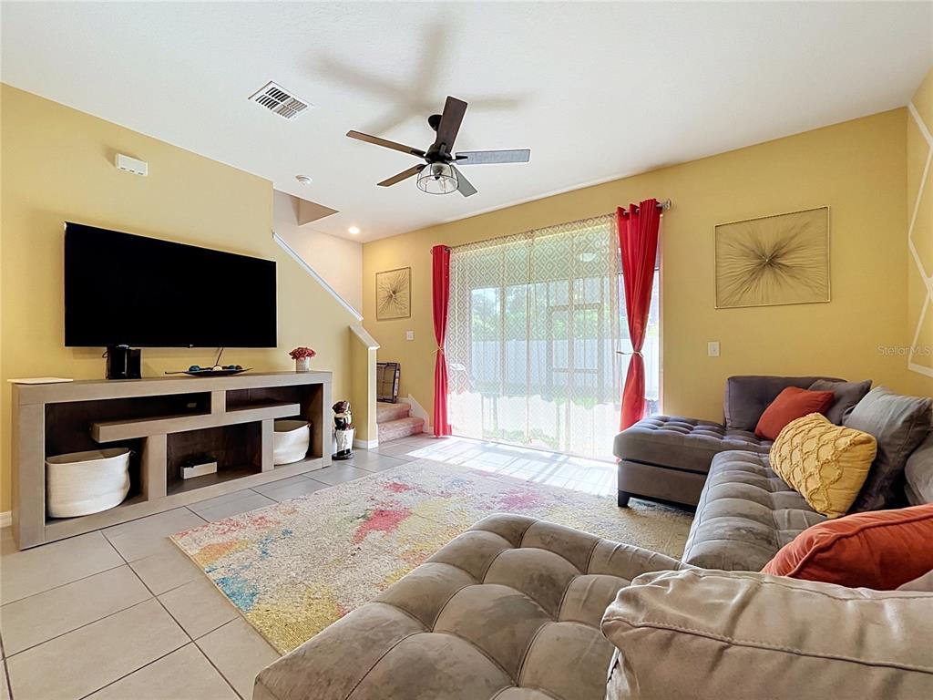 A living room features a large sectional sofa, a television console, and a sliding glass door — 3221 PLEASANT WILLOW COURT, BRANDON, FL