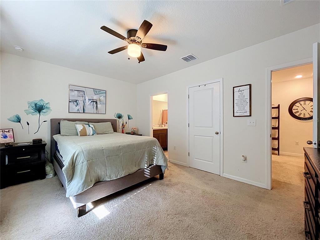 A bedroom features a bed, a ceiling fan, two doorways, and a wall-mounted clock — 3221 PLEASANT WILLOW COURT, BRANDON, FL