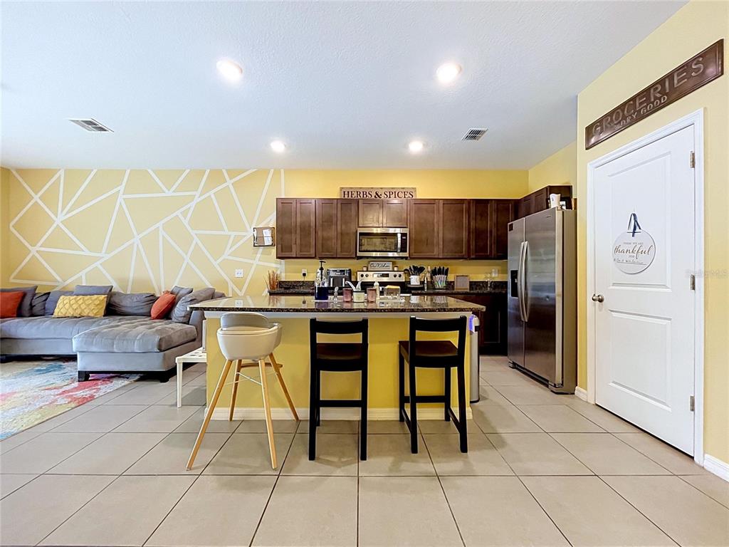 A kitchen with dark wood cabinets, a granite island, and a yellow accent wall — 3221 PLEASANT WILLOW COURT, BRANDON, FL