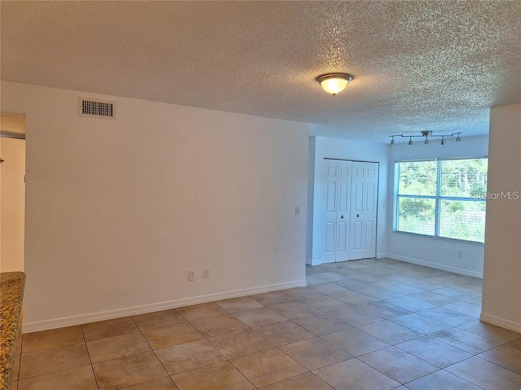 A room with light-colored tile flooring, white walls, a ceiling light, and a window — 5116 CONROY ROAD UNIT 12, ORLANDO, FL