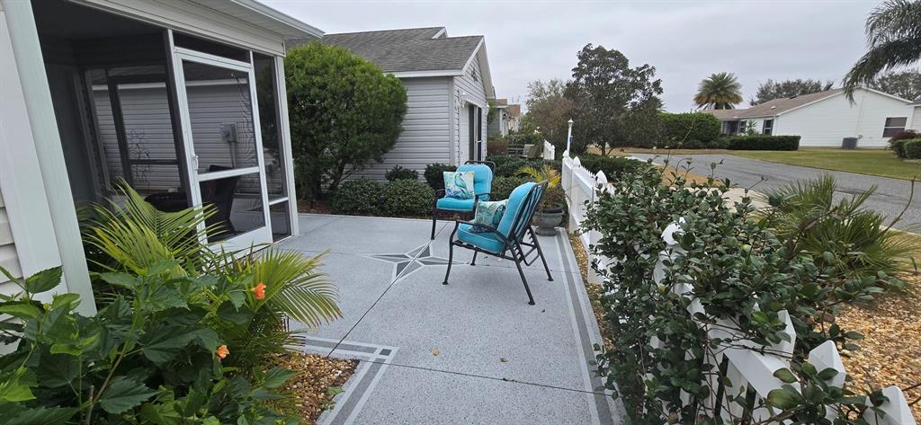 A patio with a compass rose design features two blue chairs and a white fence — 1846 KANE PLACE, THE VILLAGES, FL