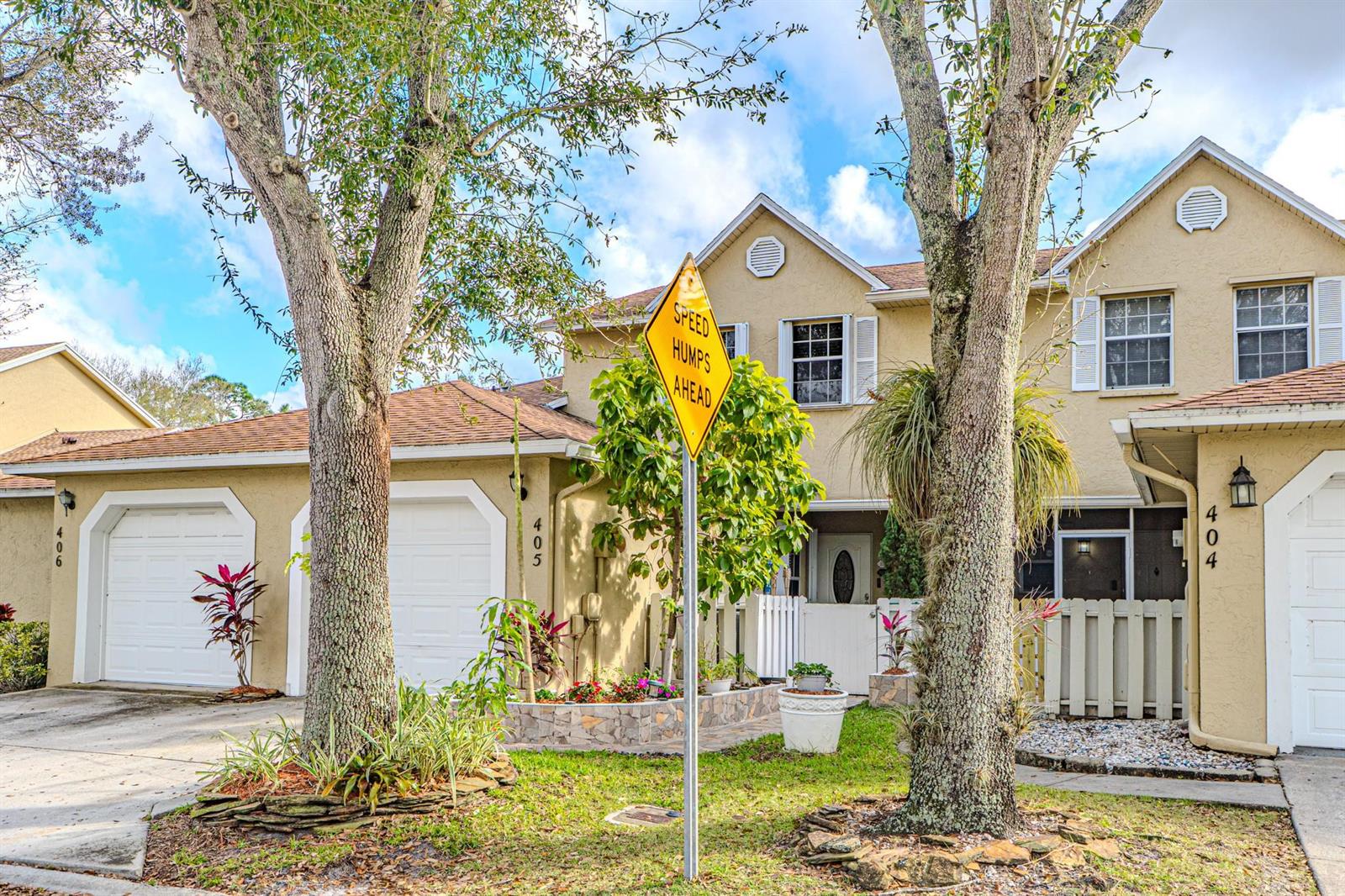 A yellow multi-unit residential building with garages and a speed hump sign in front — 405 Maplewood Drive # 405, FL 33415, FL