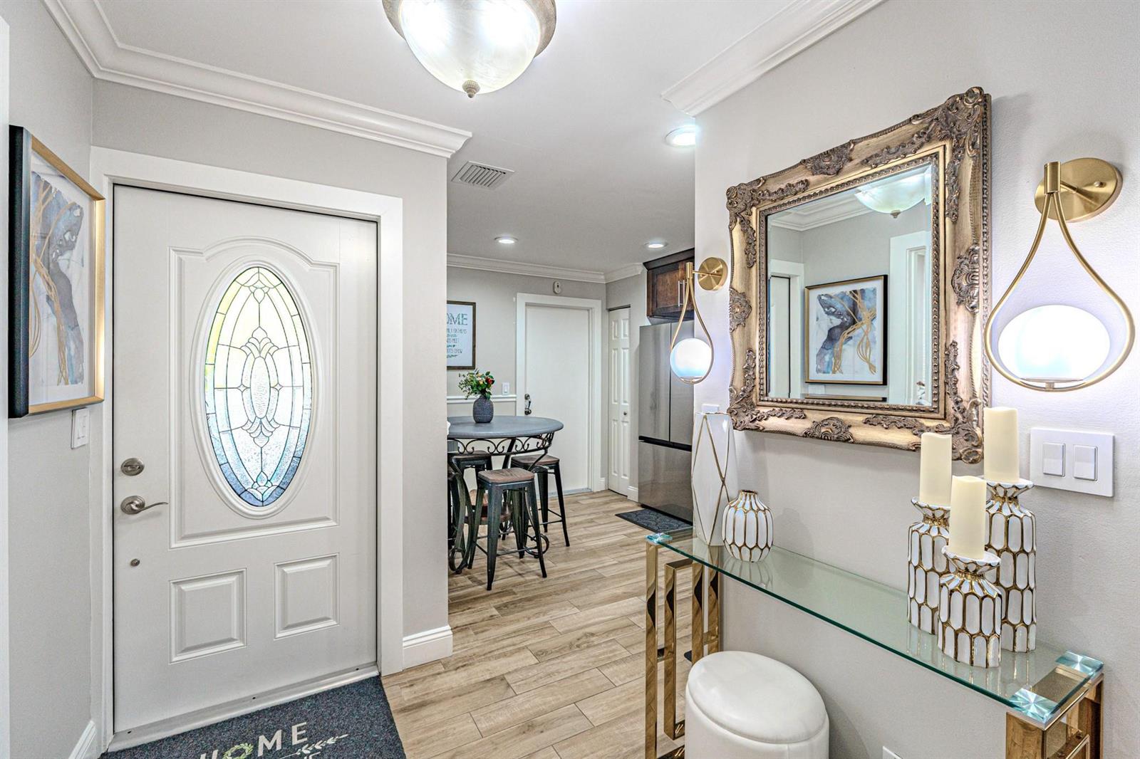 An entryway features a glass console table, a decorative mirror, and a door with glass — 405 Maplewood Drive # 405, FL 33415, FL