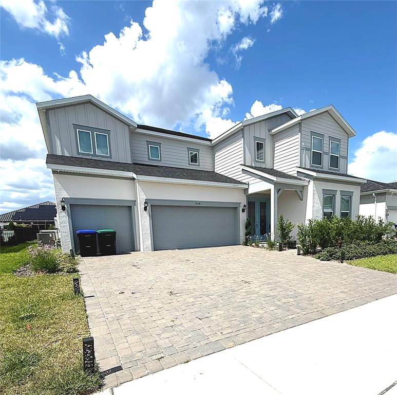 A two-story house with a paved driveway, a three-car garage, and light-colored siding — 8441 PARK CLIFF WAY, ORLANDO, FL
