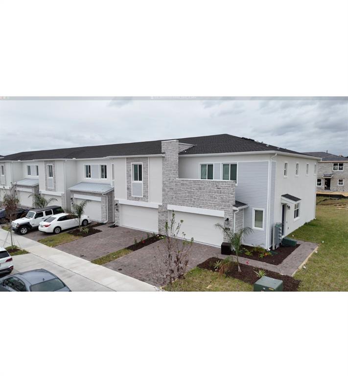 An exterior view of a multi-unit townhouse building with light siding and stone accents — 248 NINE IRON DRIVE, DAVENPORT, FL