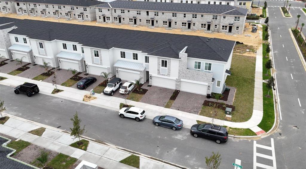 An aerial view shows a row of modern townhouses with attached garages and parked cars — 248 NINE IRON DRIVE, DAVENPORT, FL
