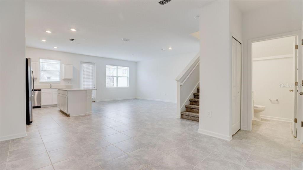 An open-concept kitchen and living area with tile flooring, white cabinets, and a staircase — 248 NINE IRON DRIVE, DAVENPORT, FL