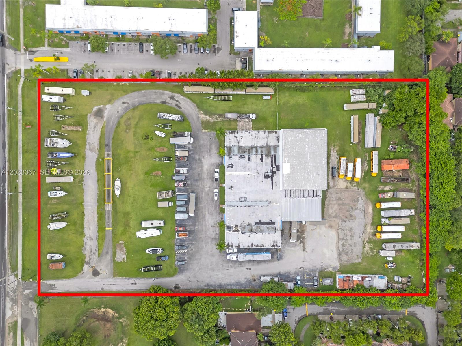An aerial view shows a commercial property with a warehouse, parking lot, and outdoor storage — 150 SW 14th Ave, Homestead FL 33030, HOMESTEAD, FL