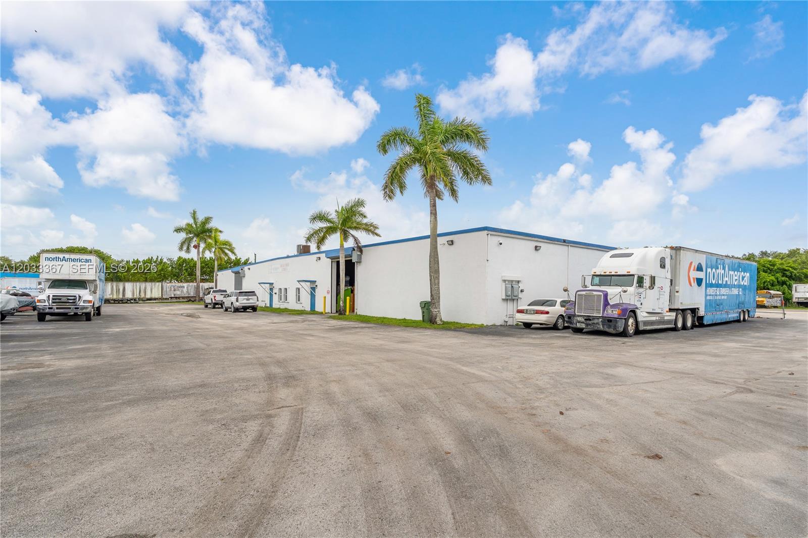 A white industrial warehouse building features a large paved lot with several parked trucks — 150 SW 14th Ave, Homestead FL 33030, HOMESTEAD, FL