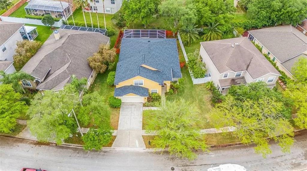 An aerial view shows a yellow house with a dark roof and a screened-in pool — 19151 DOVE CREEK DRIVE, TAMPA, FL