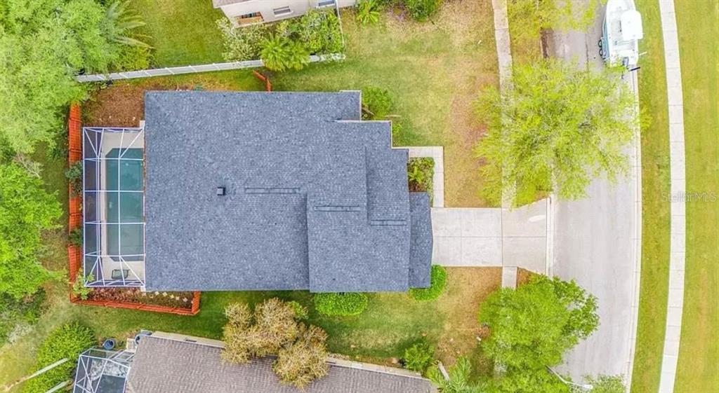 An aerial view shows a house with a shingled roof, a screened pool, and a driveway — 19151 DOVE CREEK DRIVE, TAMPA, FL