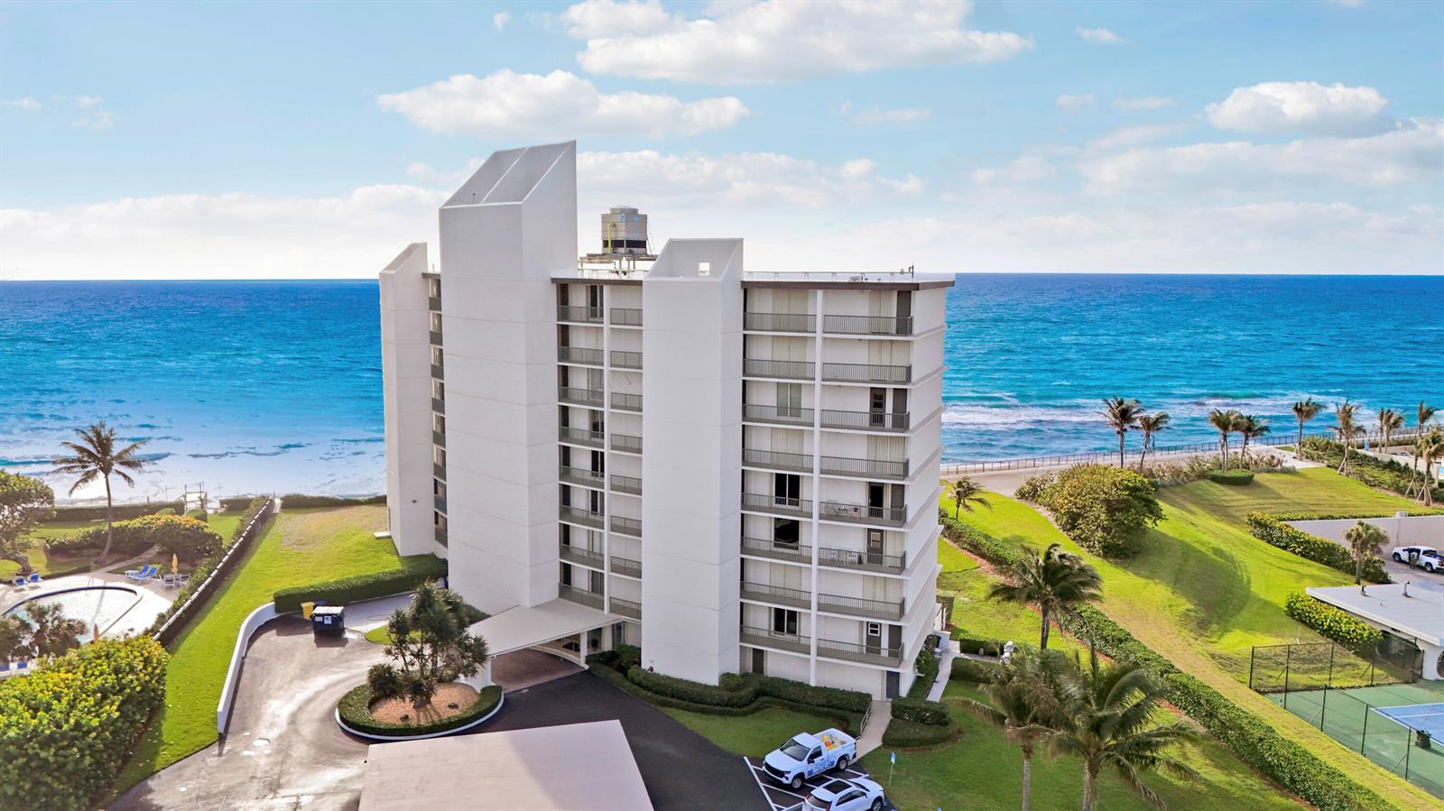An aerial view of a white multi-story apartment building situated next to the ocean — 5400 N Ocean Drive # 1b, Riviera Beach FL 33404, RIVIERA BEACH, FL